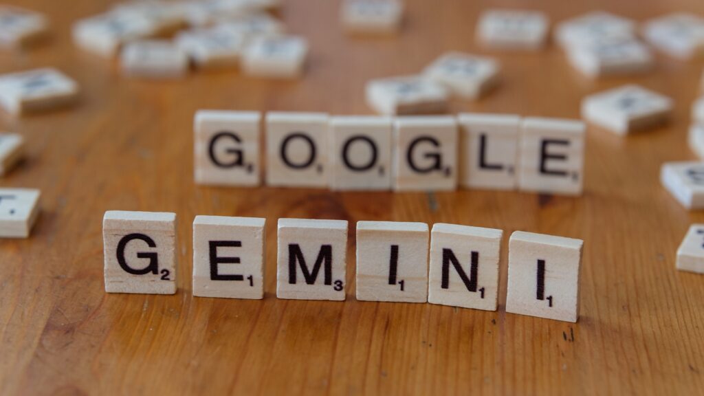 A wooden table topped with scrabble tiles spelling google, gemini,